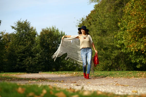 Jovem mulher na moda jeans azul e saco vermelho andando no outono — Fotografia de Stock