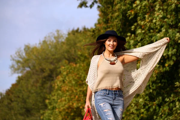 Young woman in fashion blue jeans and red bag walking in autumn — Stock Fotó