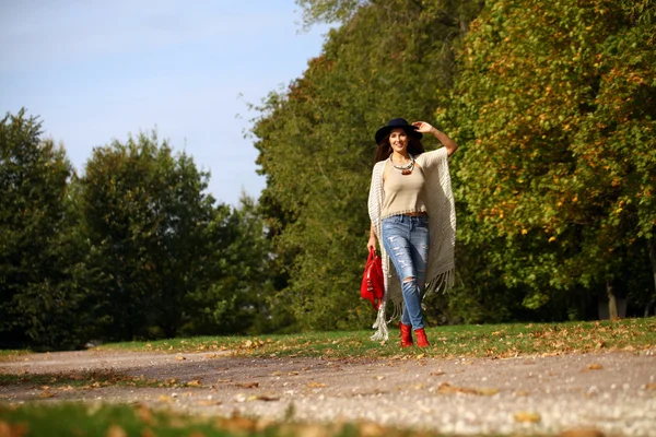 Jovem mulher na moda jeans azul e saco vermelho andando no outono — Fotografia de Stock