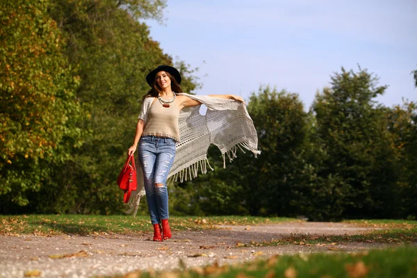 Молодая женщина в модных синих джинсах и красной сумке ходить осенью — стоковое фото