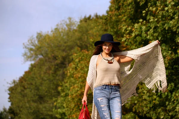 Jovem mulher na moda jeans azul e saco vermelho andando no outono — Fotografia de Stock