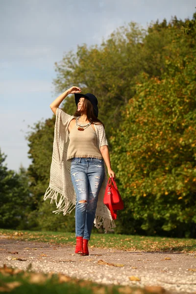 Jovem mulher na moda jeans azul e saco vermelho andando no outono — Fotografia de Stock