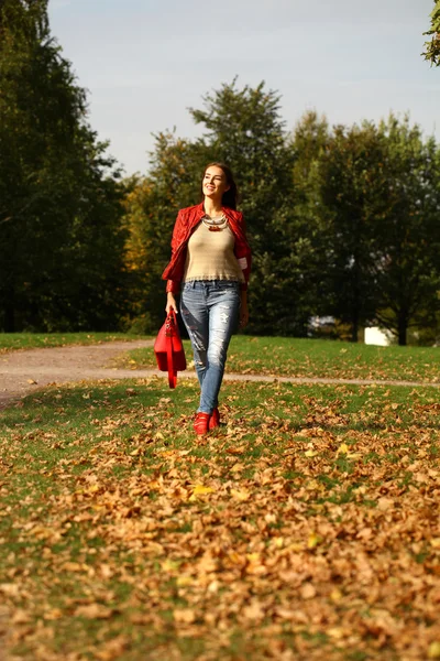 Jeune femme à la mode veste rouge et sac rouge marche en automne — Photo