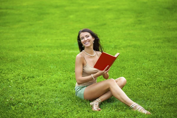 Jeune belle fille brune lisant un livre en plein air — Photo