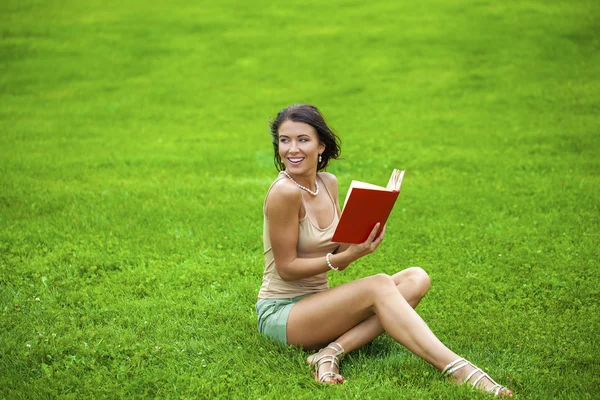 Jeune belle fille brune lisant un livre en plein air — Photo