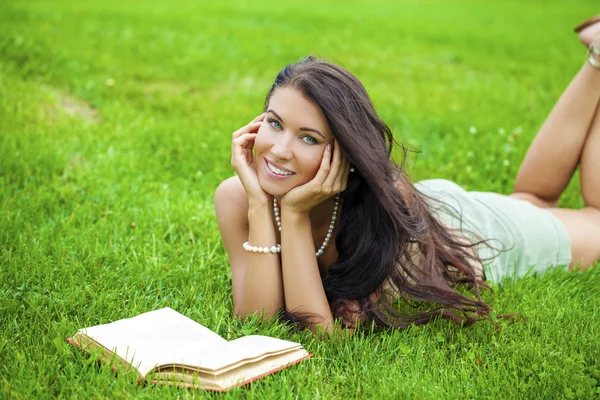 Jeune belle fille brune lisant un livre en plein air — Photo