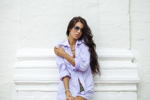 Fashion portrait of young brunette model posing by the wall — Stock Photo, Image