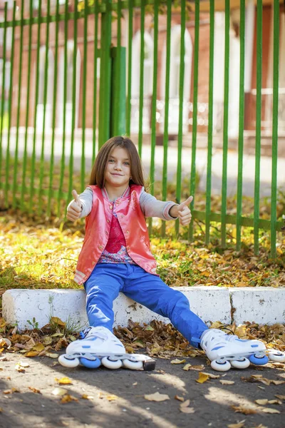 Küçük kız portresi bir oyun alanında tekerlekli paten oturur — Stok fotoğraf