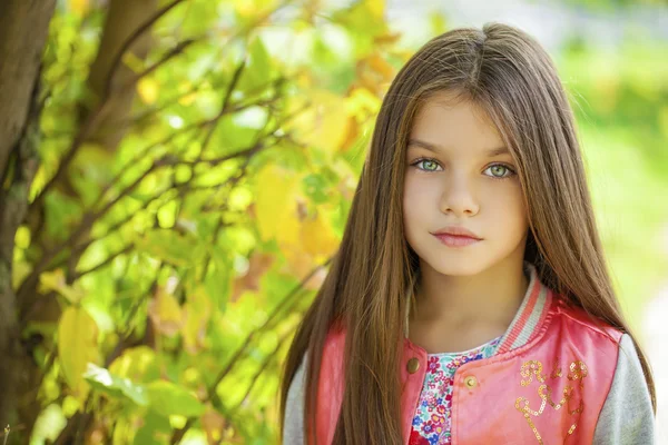Schönes kleines Mädchen auf grünem Hintergrund des Sommer-Stadtparks — Stockfoto