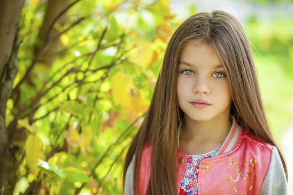 Hermosa niña en el fondo verde del parque de la ciudad de verano —  Fotos de Stock