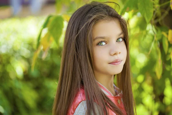 Beautiful little girl on green background of summer city park — Stock Photo, Image