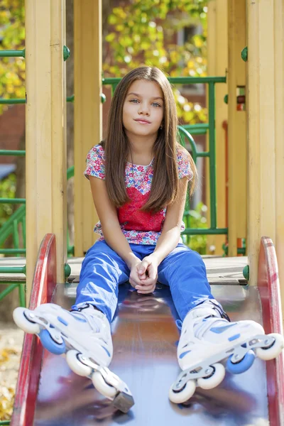 Küçük kız portresi bir oyun alanında tekerlekli paten oturur — Stok fotoğraf