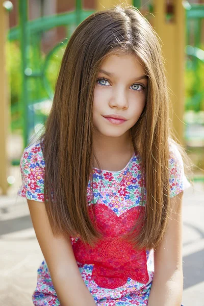 Schönes kleines Mädchen auf grünem Hintergrund des Sommer-Stadtparks — Stockfoto