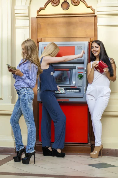 Bir otomatik vezne makinesi kullanarak üç genç mutlu kadın — Stok fotoğraf