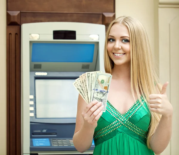 Blonde woman in a green dress is holding a cash dollars — Stock Photo, Image