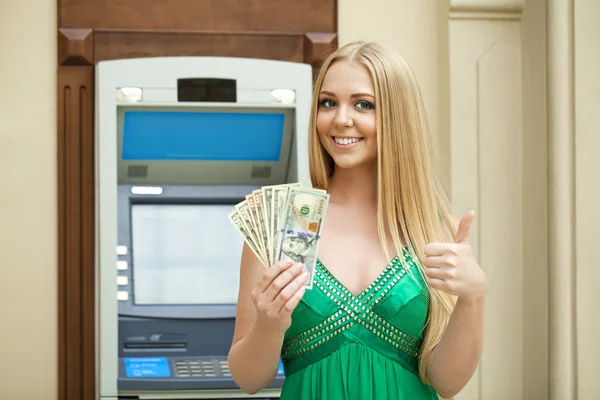 Blonde woman in a green dress is holding a cash dollars — Stock Photo, Image