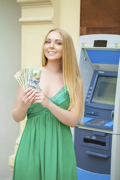 Femme blonde dans une robe verte tient un argent comptant dollars — Photo