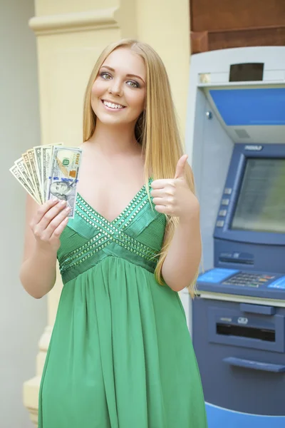 Blond kvinna i en grön klänning håller en kontant dollar — Stockfoto