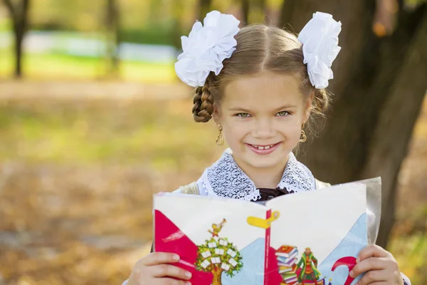 Счастливая маленькая школьница в осеннем парке — стоковое фото