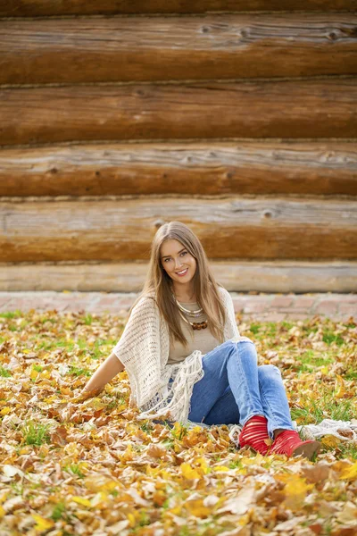 Felice bella donna in jeans blu seduta nel parco autunnale — Foto Stock