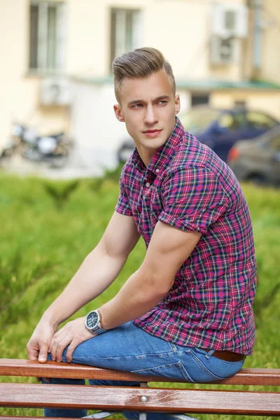 Ruhiger, gutaussehender Mann im karierten Hemd auf dem Hintergrund der Sommerstraße — Stockfoto