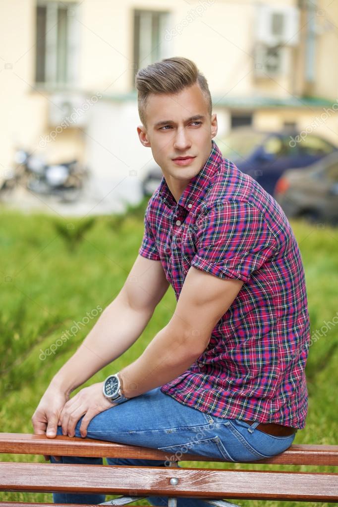 Calm handsome man in plaid shirt on the background of summer str