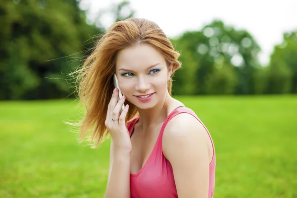 Hermosa mujer joven sonriente pelirroja hablando en un teléfono celular —  Fotos de Stock