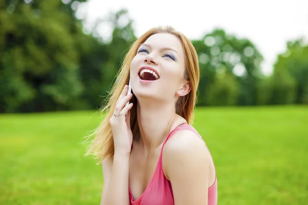 Hermosa mujer joven sonriente pelirroja hablando en un teléfono celular —  Fotos de Stock