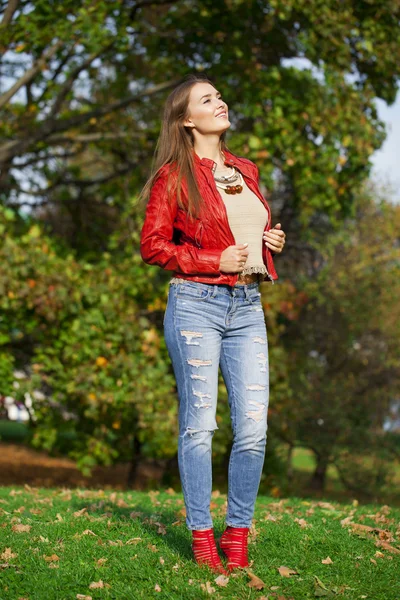 Jeune femme à la mode veste rouge et jeans bleus marchant en autu — Photo