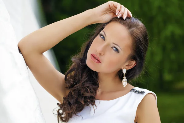 Retrato de la hermosa chica triste en vestido blanco apoyado en el wal — Foto de Stock