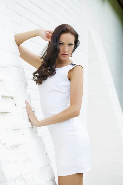 Porträtt av vacker ledsen flicka i vit klänning lutande på wal — Stockfoto