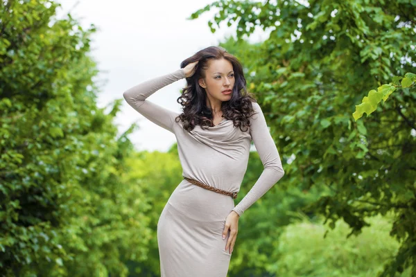 Krásná mladá žena v sexy dlouhé šedé šaty v letním parku — Stock fotografie
