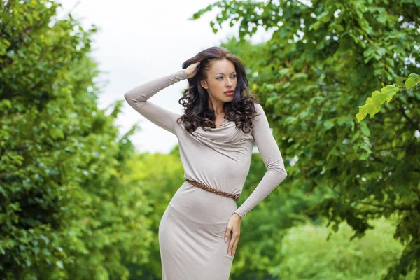 Hermosa mujer joven en vestido gris largo sexy en el parque de verano — Foto de Stock