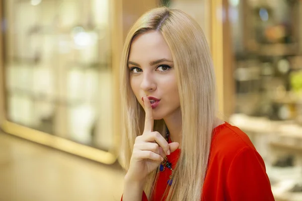Retrato de jovem mulher loira atraente com o dedo nos lábios — Fotografia de Stock