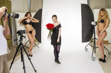 Photoshoot with a bouquet of red roses. Young beautiful women po