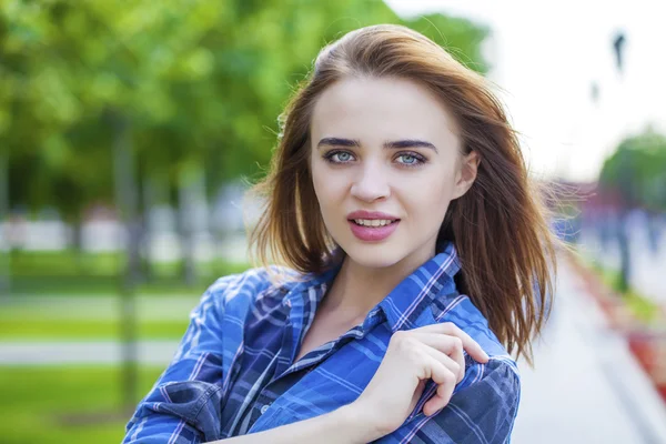 Close up of young beautiful woman in a checkered blue shirt — Stock Photo, Image