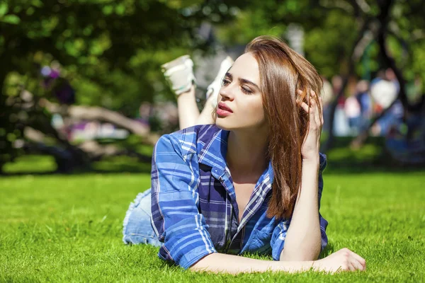 Mladá krásná hnědovlasá žena ležící na trávníku — Stock fotografie