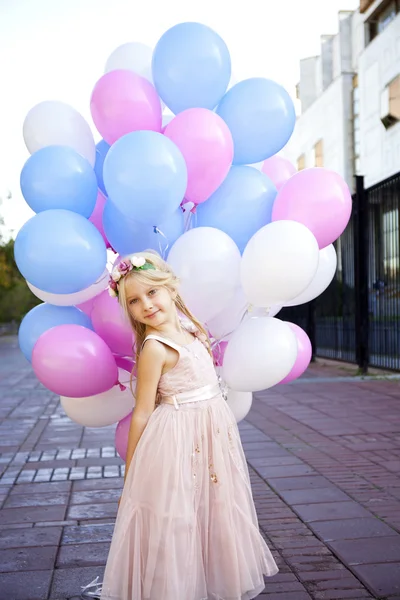 Niña de cinco años con un vestido rosa sosteniendo globos — Foto de Stock