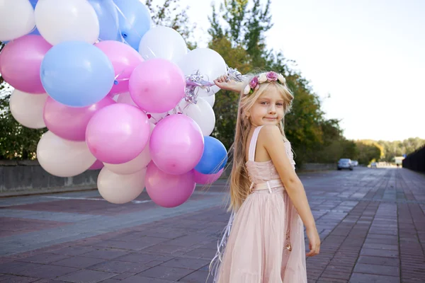 Niña de cinco años con un vestido rosa sosteniendo globos — Foto de Stock