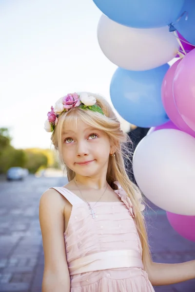 Niña de cinco años con un vestido rosa sosteniendo globos — Foto de Stock