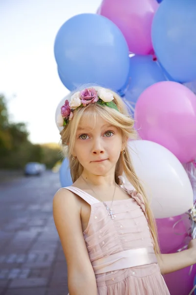 Pequena menina de cinco anos em um vestido rosa segurando balões — Fotografia de Stock