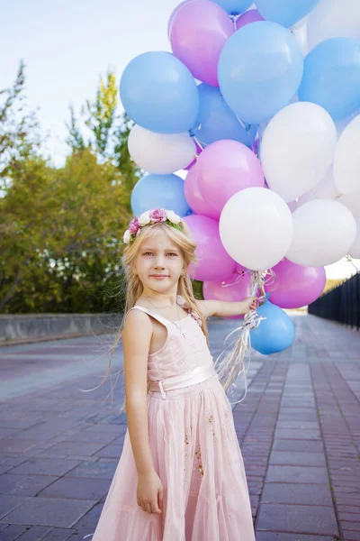 Niña de cinco años con un vestido rosa sosteniendo globos —  Fotos de Stock