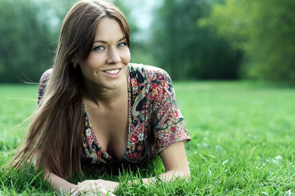 Portrait of young woman lying on a green lawn — Stock Photo, Image