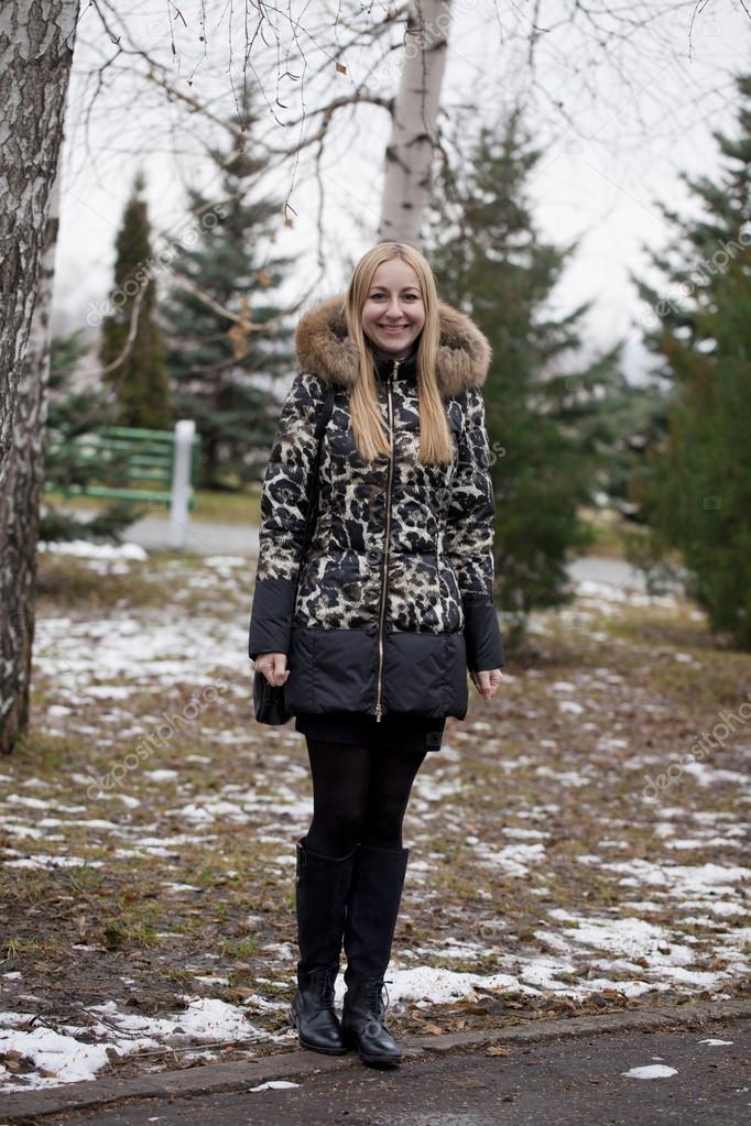Happy young blonde woman on the background of a winter park
