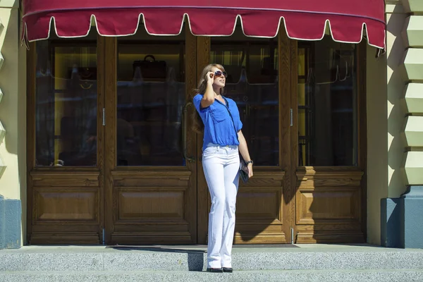Kadın beyaz pantolon ve bluz s arka plan üzerinde poz — Stok fotoğraf