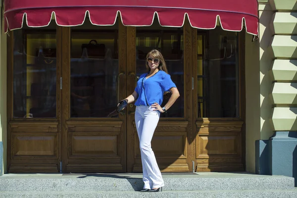 Mujer en pantalones blancos y blusa posando sobre el fondo de s — Foto de Stock