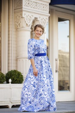 Mavi elbiseli bir arka planda poz güzel sarışın kız 