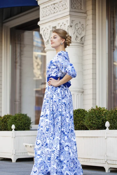 Schöne blonde Mädchen in blauem Kleid posiert vor einem Hintergrund — Stockfoto