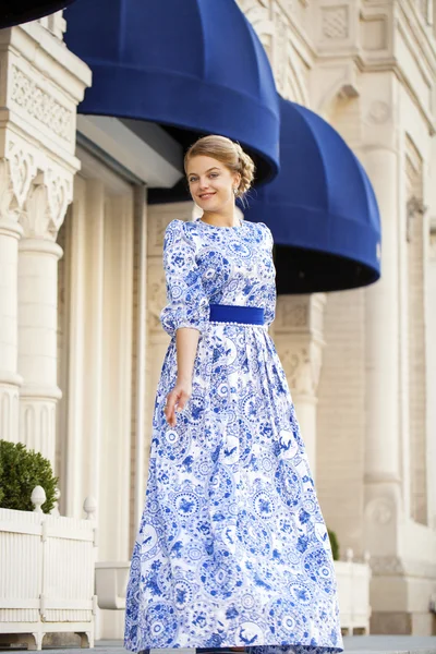 Hermosa chica rubia en vestido azul posando sobre un fondo — Foto de Stock
