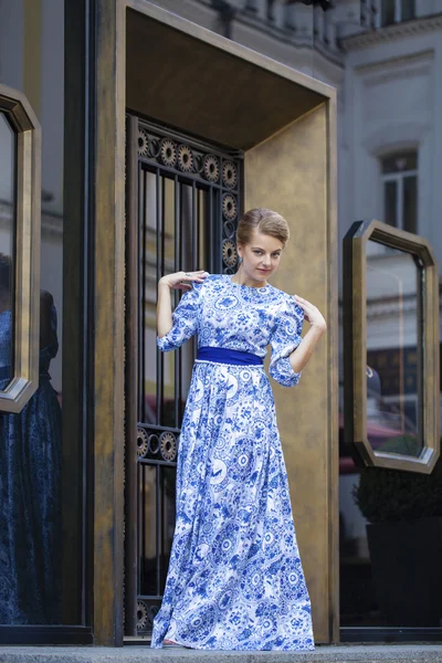 Όμορφη ξανθιά κοπέλα σε μπλε φόρεμα θέτουν σε φόντο — Φωτογραφία Αρχείου